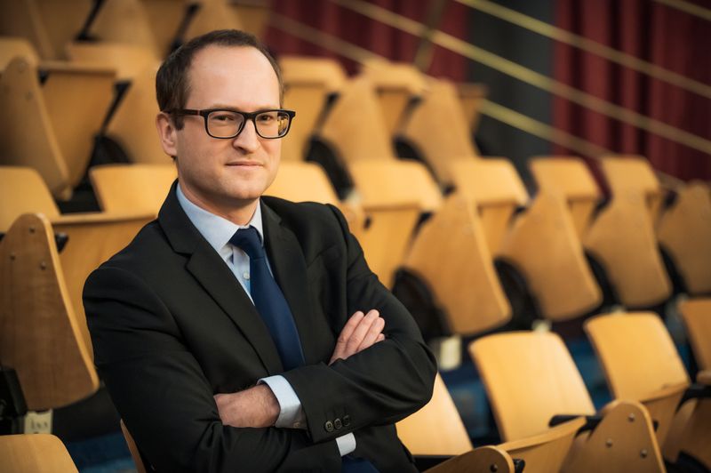 Tomas Havranek (Tomáš Havránek), in a lecture hall, arms crossed, 2022